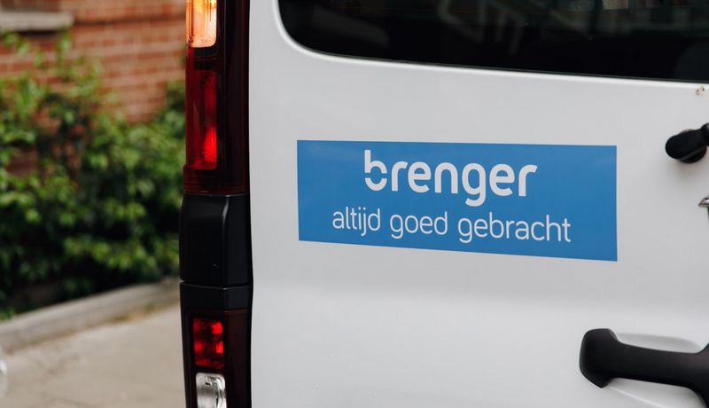 Brenger koeriersbusje met het logo en de tekst 'altijd goed gebracht' geparkeerd naast een stoep.